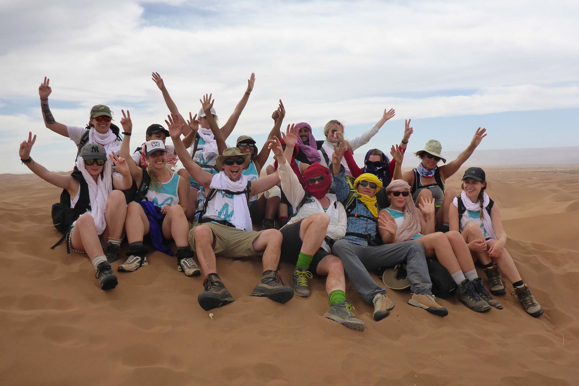 A group of travellers waving from a sand dune